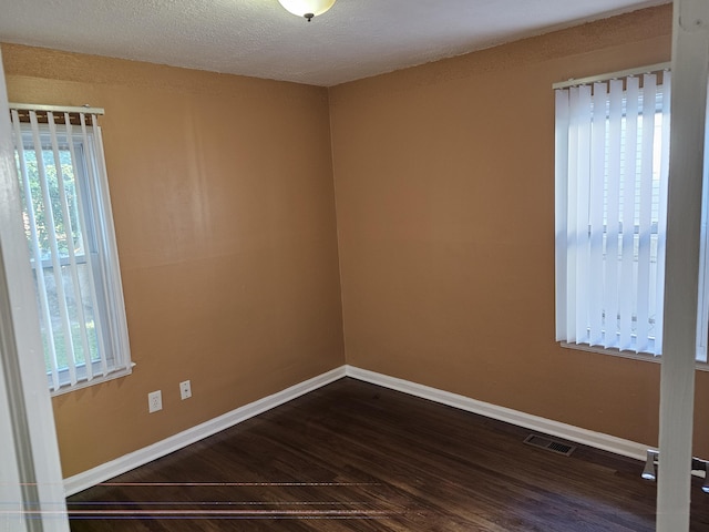 empty room featuring dark wood-type flooring and a textured ceiling