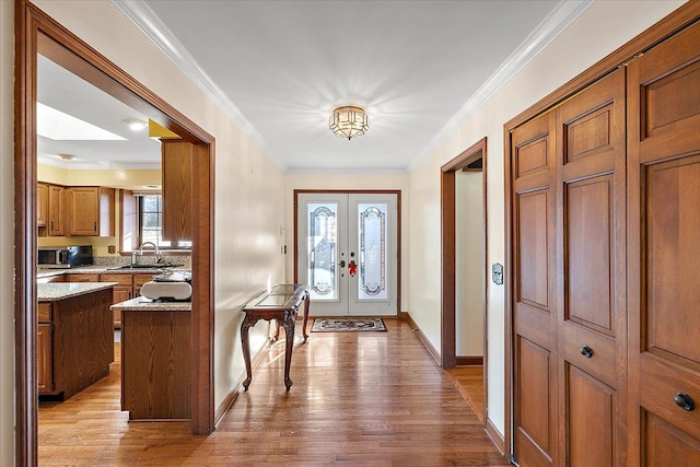 entrance foyer featuring crown molding, french doors, sink, and light wood-type flooring