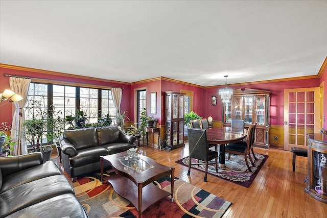 living room featuring a chandelier, light hardwood / wood-style floors, and crown molding