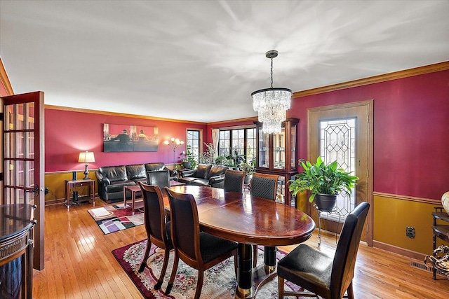 dining room with light hardwood / wood-style floors, crown molding, and a notable chandelier