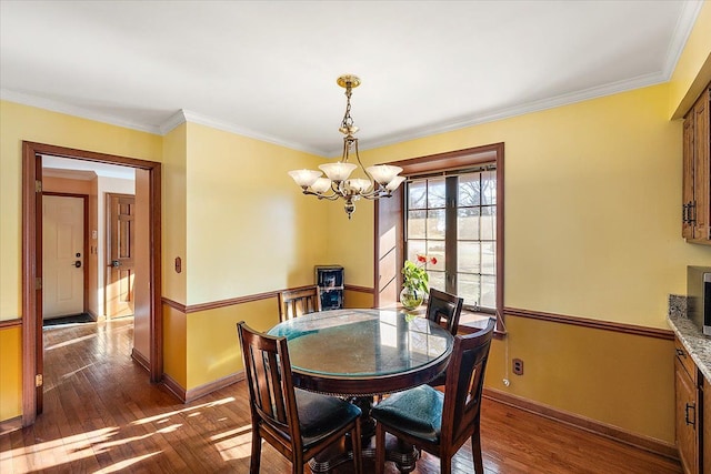 dining area featuring crown molding, dark wood-type flooring, and a chandelier