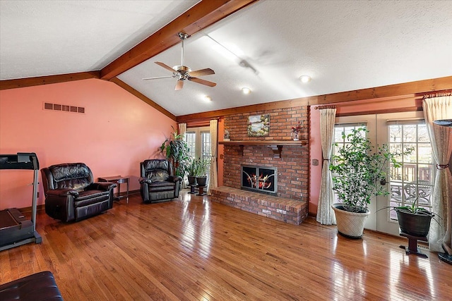 living room with a fireplace, vaulted ceiling with beams, a textured ceiling, and plenty of natural light