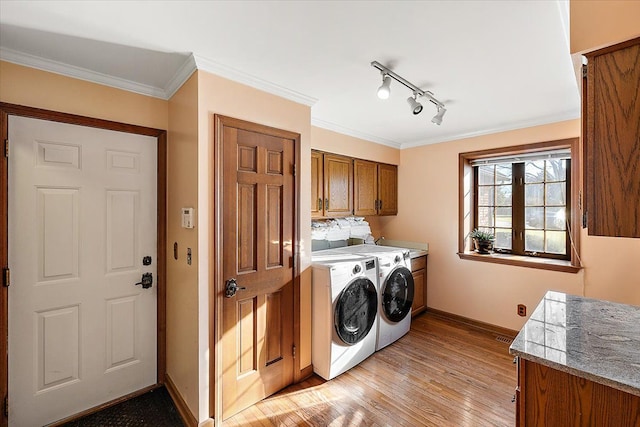 laundry room with cabinets, rail lighting, crown molding, washer and dryer, and light hardwood / wood-style floors