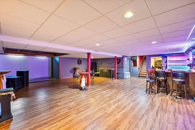 rec room with a paneled ceiling, wood-type flooring, and indoor bar