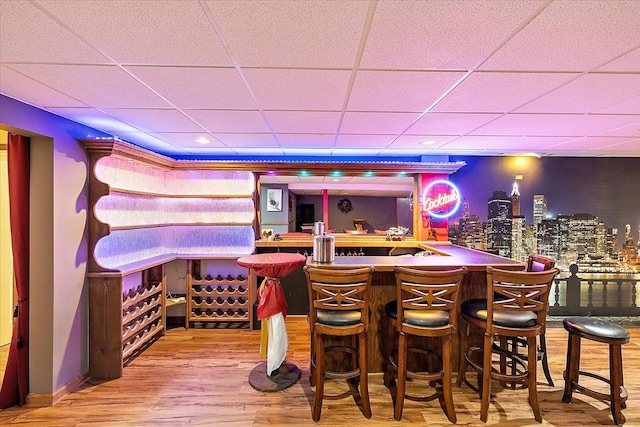 bar with a drop ceiling and wood-type flooring