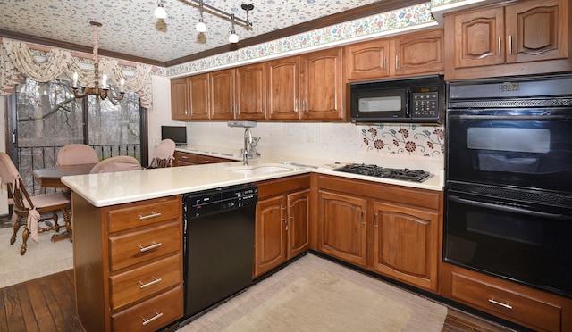 kitchen with sink, decorative light fixtures, light wood-type flooring, kitchen peninsula, and black appliances