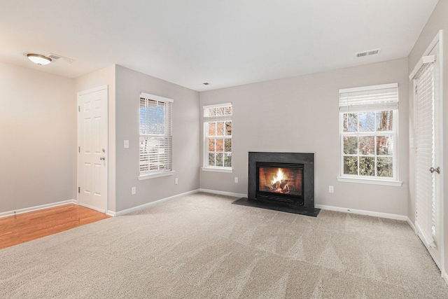 unfurnished living room featuring light colored carpet and a wealth of natural light