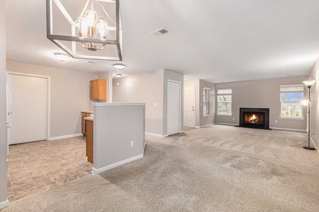 unfurnished living room with light colored carpet and a notable chandelier