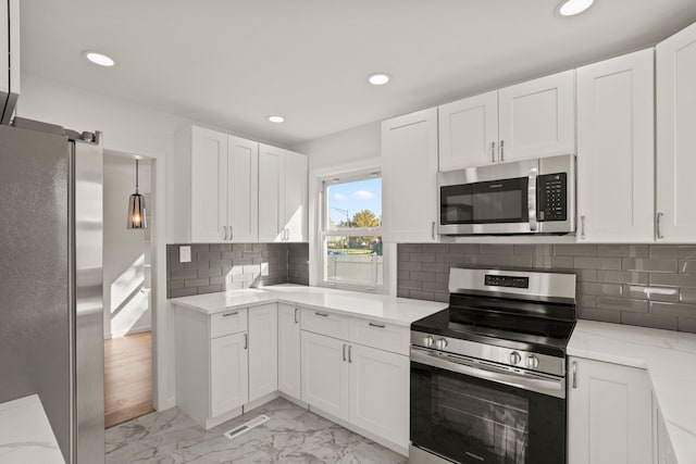 kitchen with white cabinets, backsplash, light stone counters, and stainless steel appliances