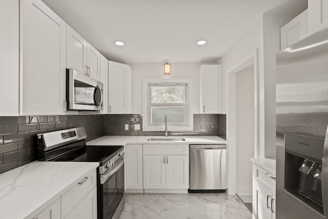 kitchen with decorative backsplash, light stone counters, stainless steel appliances, sink, and white cabinets