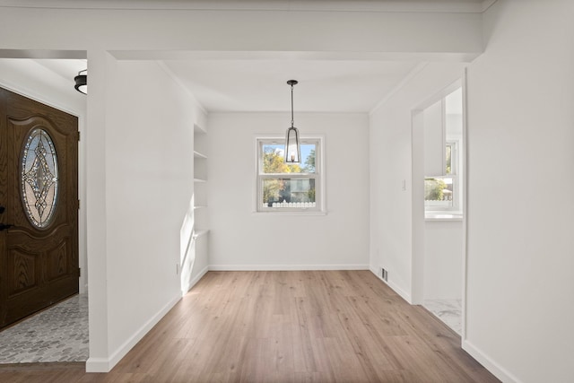 unfurnished dining area with light wood-type flooring, built in features, and crown molding