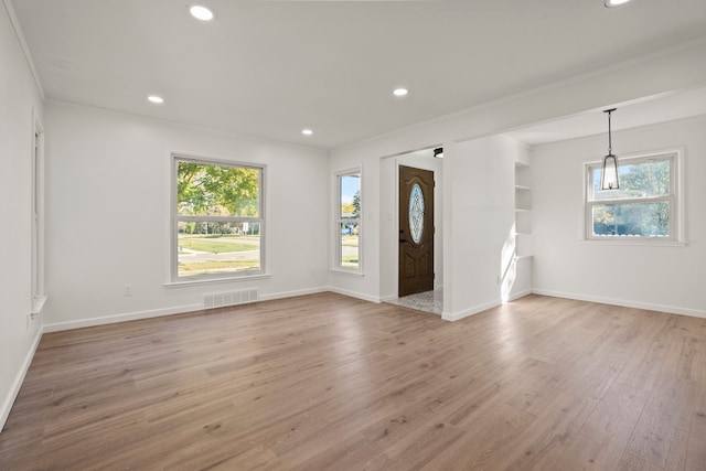 unfurnished room featuring ornamental molding, light hardwood / wood-style floors, built in features, and a healthy amount of sunlight