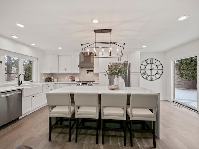 kitchen with sink, a center island, stainless steel appliances, wall chimney range hood, and a breakfast bar