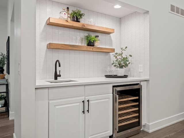 bar with backsplash, dark wood-type flooring, sink, white cabinetry, and beverage cooler