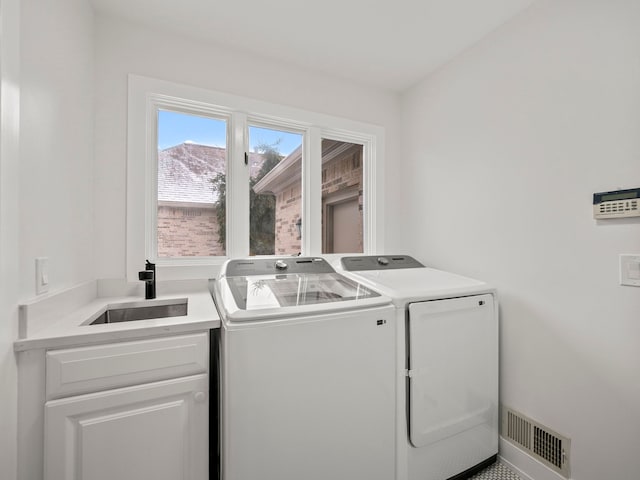 laundry area featuring washer and clothes dryer, sink, and cabinets