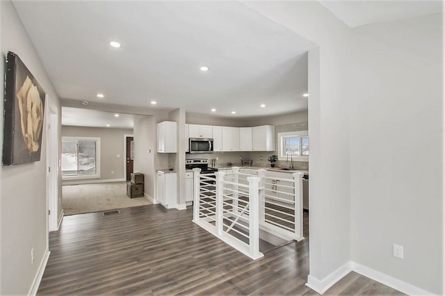 kitchen with stainless steel appliances, white cabinetry, sink, and dark wood-type flooring