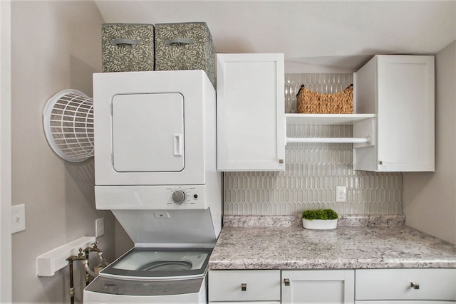 laundry room with cabinets and stacked washer / drying machine