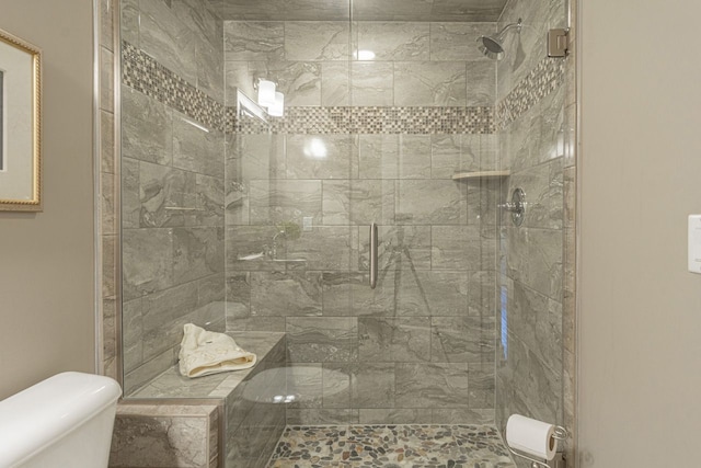 bathroom with a shower with shower door and toilet