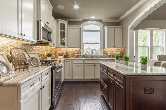 kitchen with light stone counters, stainless steel appliances, white cabinets, and sink