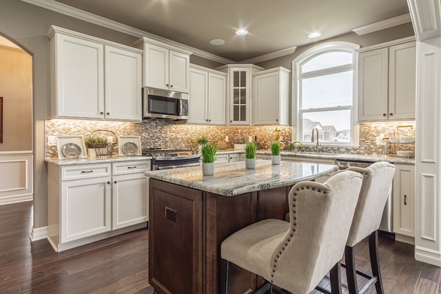 kitchen with light stone countertops, appliances with stainless steel finishes, white cabinetry, and a center island