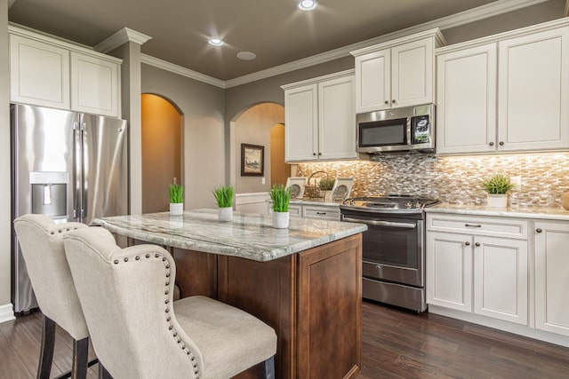 kitchen with stainless steel appliances, a center island, crown molding, and tasteful backsplash