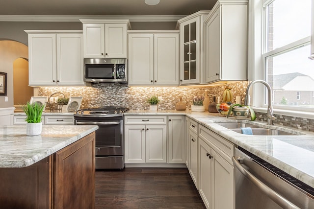 kitchen with light stone counters, appliances with stainless steel finishes, decorative backsplash, and sink