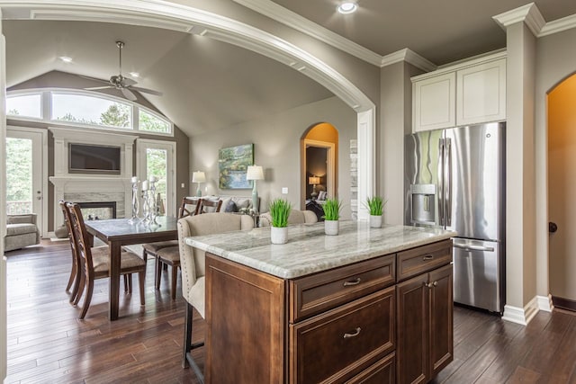 kitchen featuring a fireplace, vaulted ceiling, ceiling fan, stainless steel fridge with ice dispenser, and a kitchen island