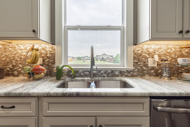 kitchen featuring light stone countertops, stainless steel dishwasher, a wealth of natural light, and sink