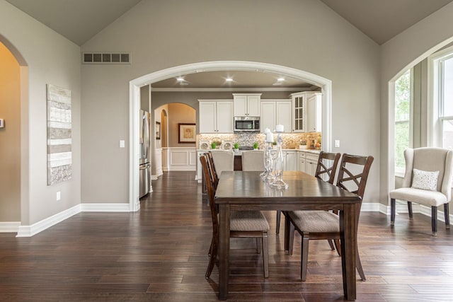 dining area with high vaulted ceiling and dark hardwood / wood-style flooring