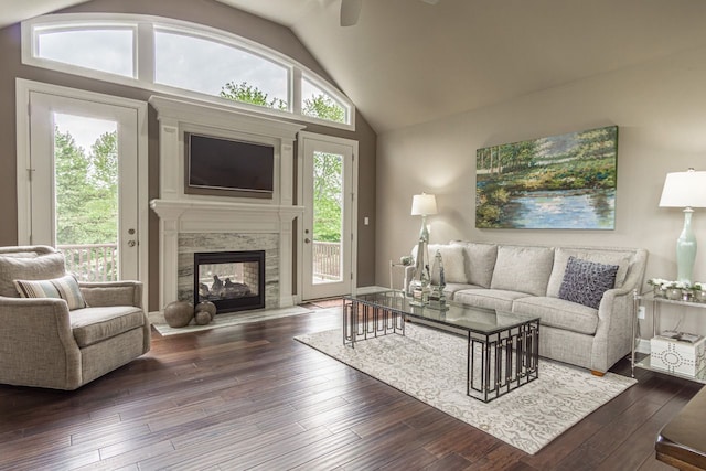 living room featuring ceiling fan, dark hardwood / wood-style flooring, a multi sided fireplace, and lofted ceiling