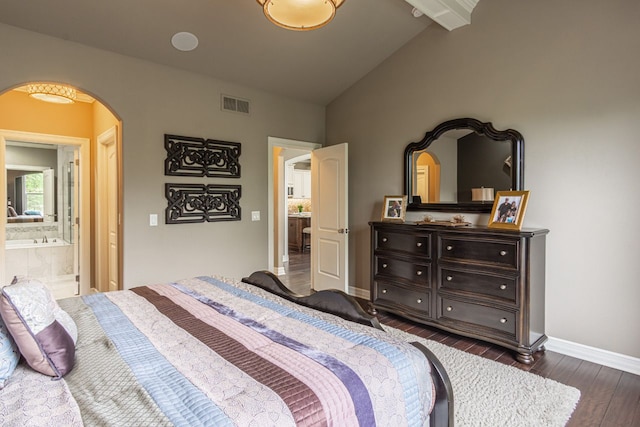 bedroom with dark hardwood / wood-style flooring, connected bathroom, and vaulted ceiling with beams