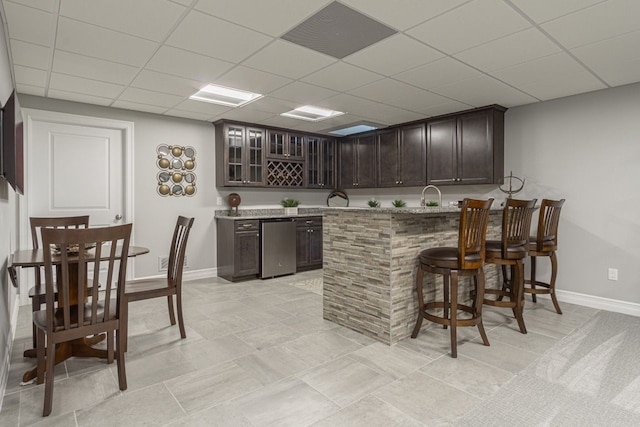 bar with a paneled ceiling, refrigerator, sink, and dark brown cabinets