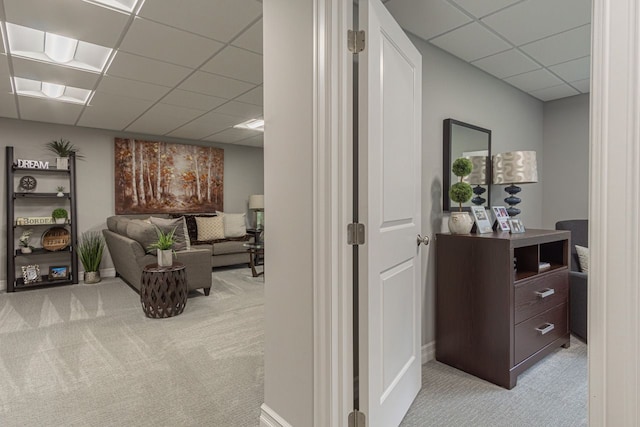 hallway featuring light carpet and a drop ceiling