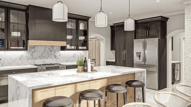 kitchen featuring light stone countertops, stainless steel fridge, stove, ornamental molding, and a kitchen island