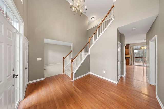 entrance foyer featuring hardwood / wood-style floors, a towering ceiling, and an inviting chandelier