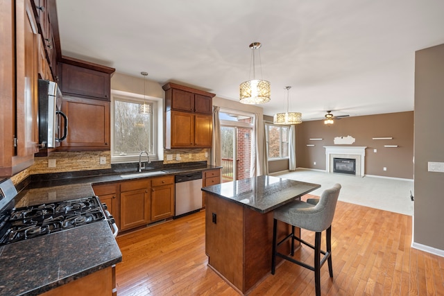 kitchen featuring sink, gas range oven, stainless steel dishwasher, pendant lighting, and a kitchen island