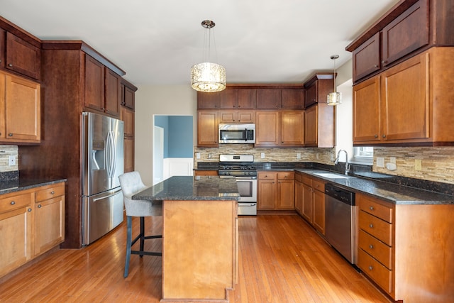 kitchen featuring light hardwood / wood-style floors, a kitchen island, hanging light fixtures, and appliances with stainless steel finishes