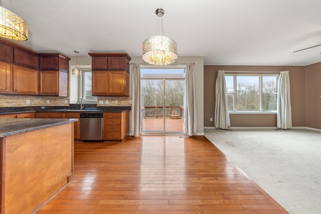 kitchen with tasteful backsplash, sink, light hardwood / wood-style flooring, dishwasher, and hanging light fixtures