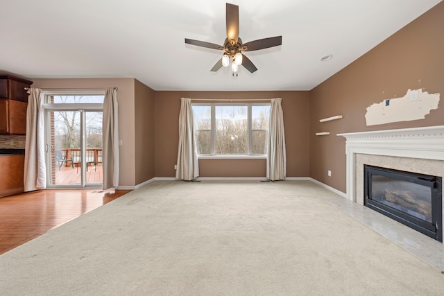 unfurnished living room with ceiling fan, a premium fireplace, and light carpet