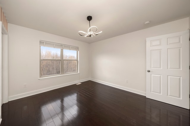 empty room featuring a chandelier and dark wood-type flooring