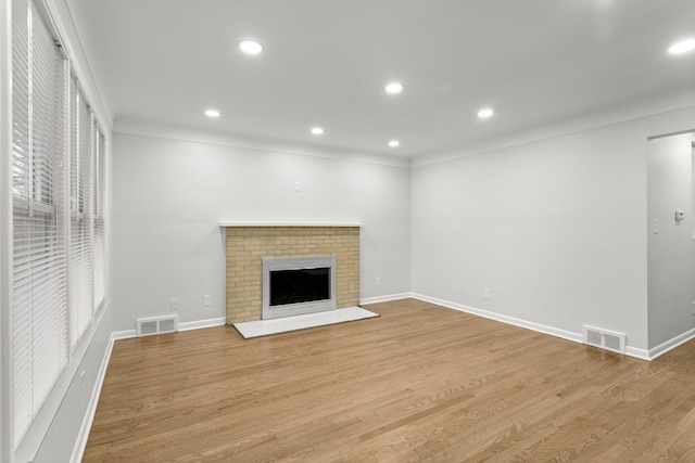 unfurnished living room with light hardwood / wood-style flooring and a brick fireplace