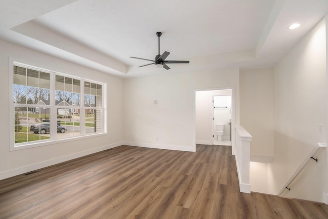 unfurnished living room with a tray ceiling, ceiling fan, and hardwood / wood-style floors