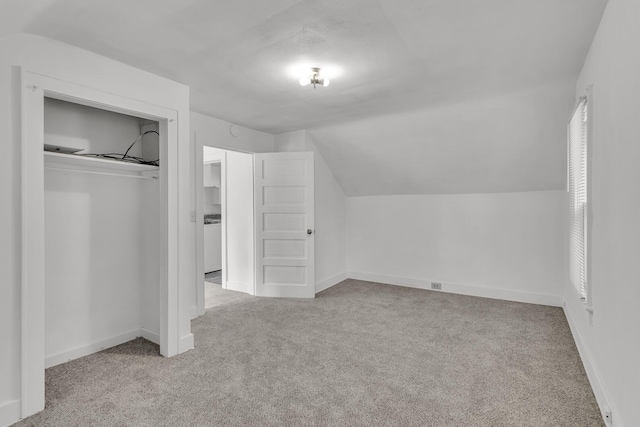 additional living space with light colored carpet, washer / clothes dryer, and vaulted ceiling