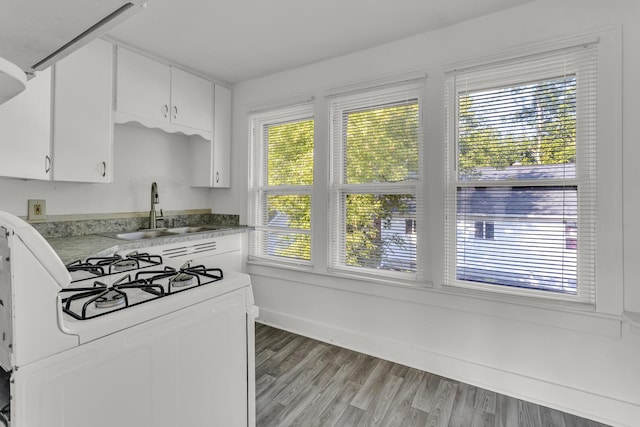 kitchen with a wealth of natural light, white cabinetry, sink, light hardwood / wood-style flooring, and white gas range oven