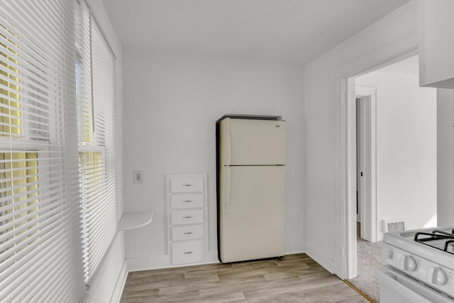 kitchen featuring white cabinets, white appliances, and light hardwood / wood-style flooring