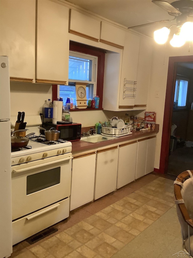 4135 Gallagher St, Saginaw, MI 48601 - kitchen featuring white appliances, white cabinetry, and a ceiling fan