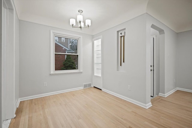 spare room featuring a notable chandelier and light hardwood / wood-style floors