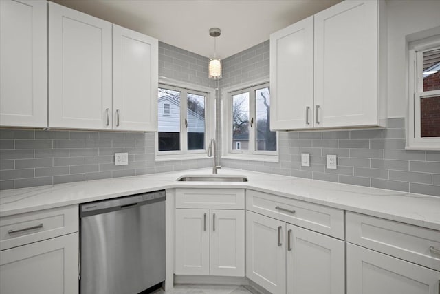 kitchen featuring light stone counters, sink, dishwasher, white cabinetry, and hanging light fixtures