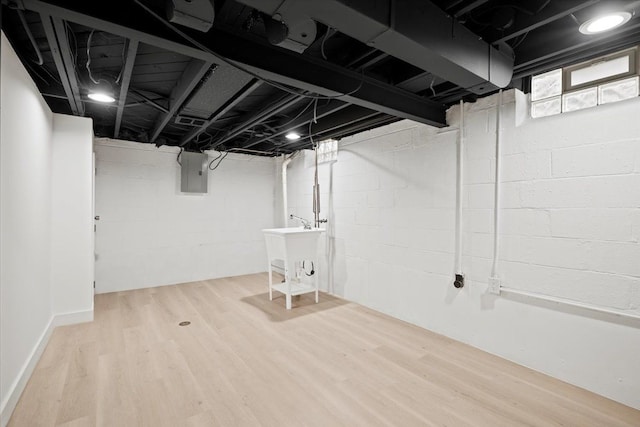 basement with electric panel, hardwood / wood-style floors, and sink