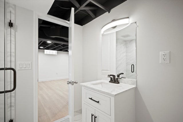 bathroom featuring a shower with door and vanity